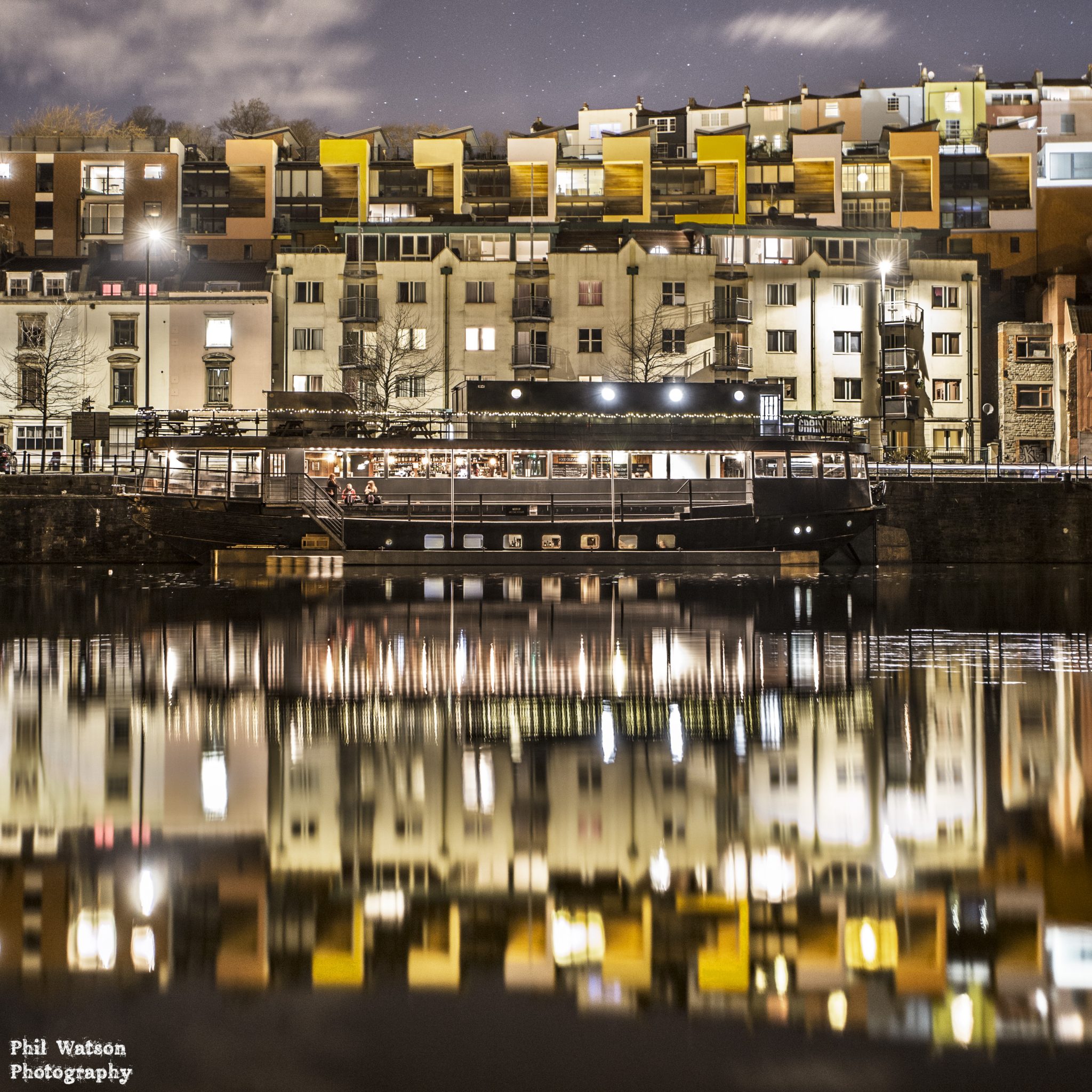 grain barge at night with street lamps and reflection on the river