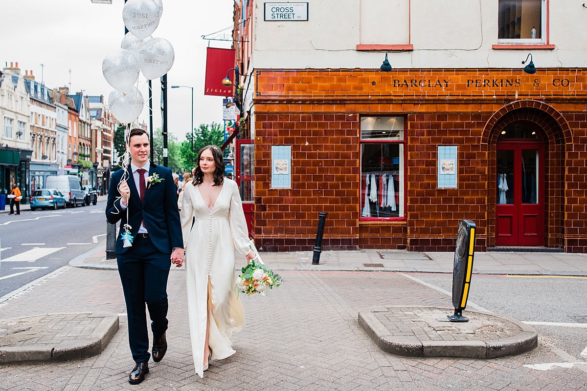 Bride and groom hold balloons crossing the road - parrot and pineapple wedding photography