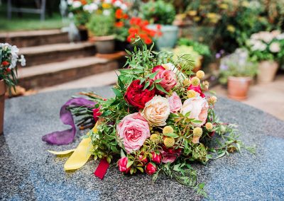 Red and pink bridal bouquet lying on a table. Image my Parrot and Pineapple.