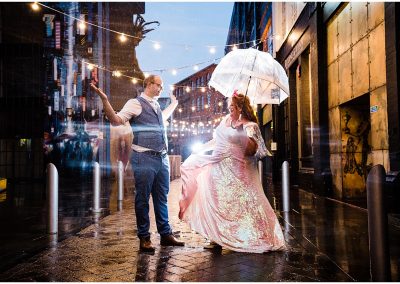 bride wearing sequin wedding dress dances with groom in the rain under umbrella at digbeth birmingham wedding