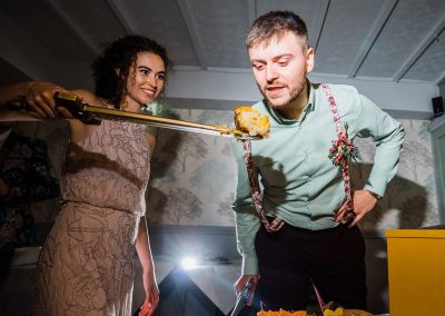 Bride feeding cake to groom with a sword small wedding